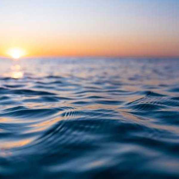 A view of the surface of the sea with the setting sun in the distance