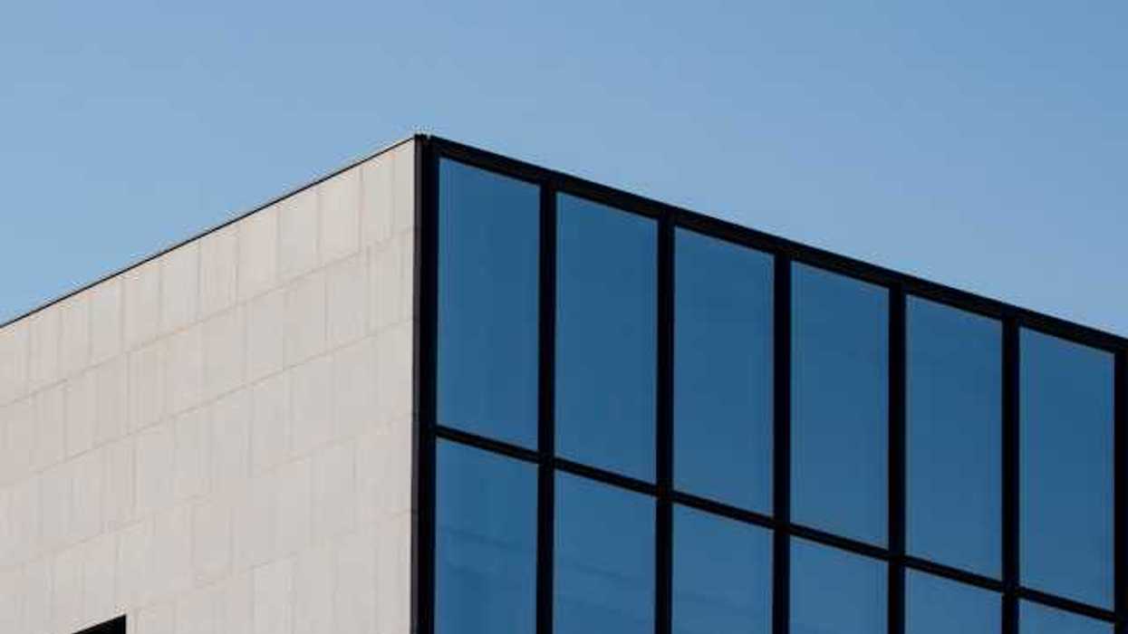 A view of the top corner of an office building with blue sky in the background