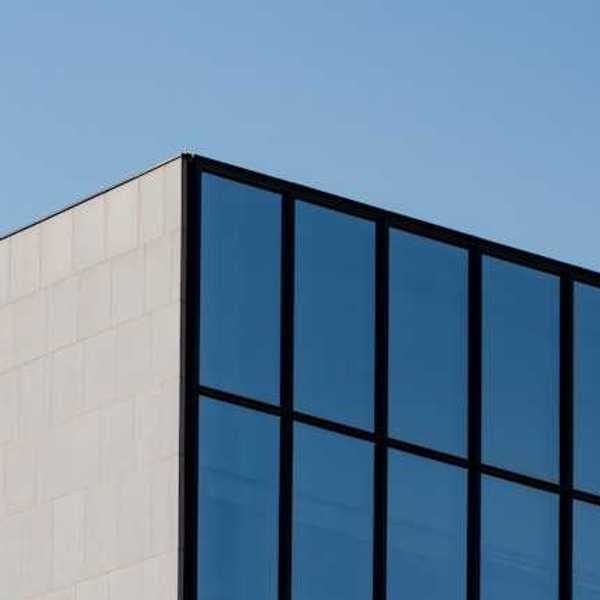 A view of the top corner of an office building with blue sky in the background