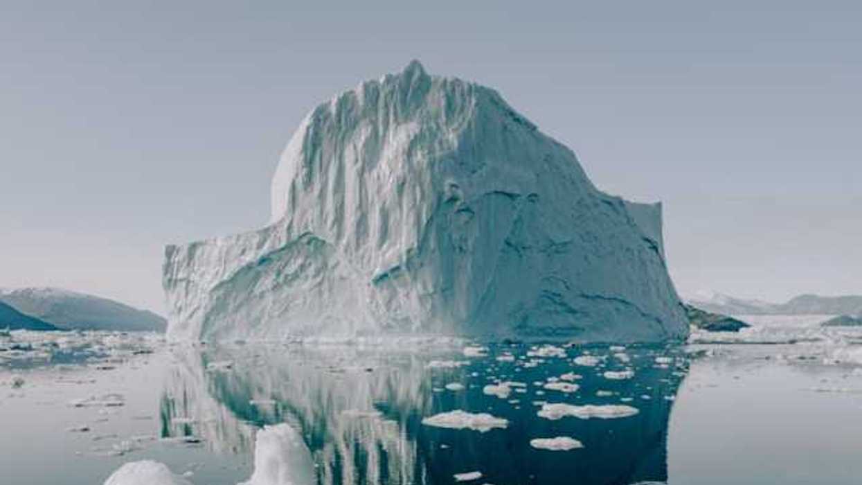 A view of water with a huge iceberg in the distance