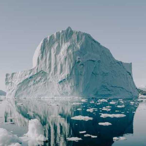 A view of water with a huge iceberg in the distance