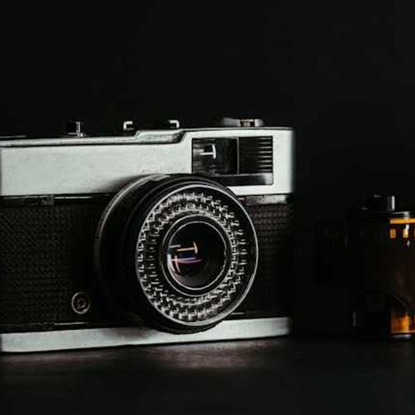 A vintage camera sitting next to a roll of camera film