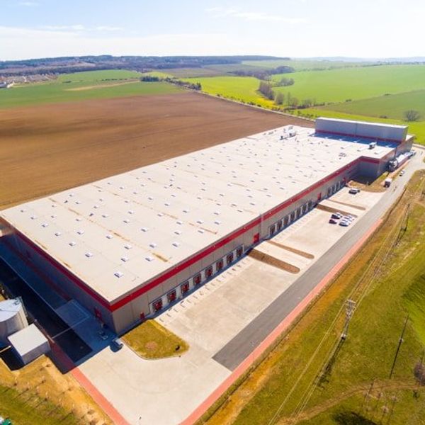 A warehouse or data center sited in the middle of green fields.