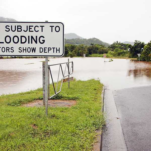 A white and black sign warning of a road subject to flooding
