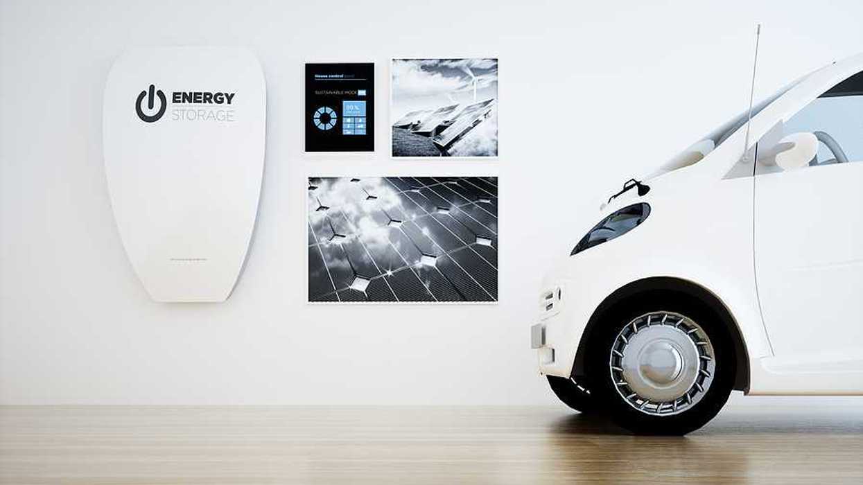 A white home energy battery installed on a wall next to a small white electric vehicle