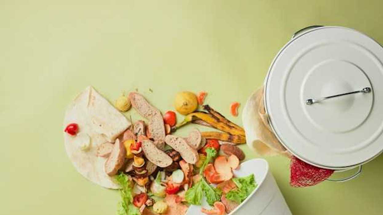 A white trash can overturned with food waste spilling out of it