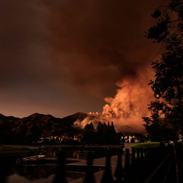A wildfire on distant hills with houses in the foreground
