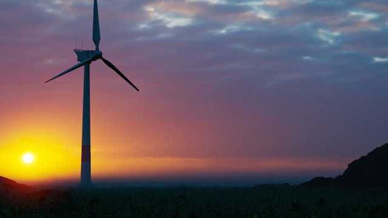 A wind turbine silhouetted against the setting sun