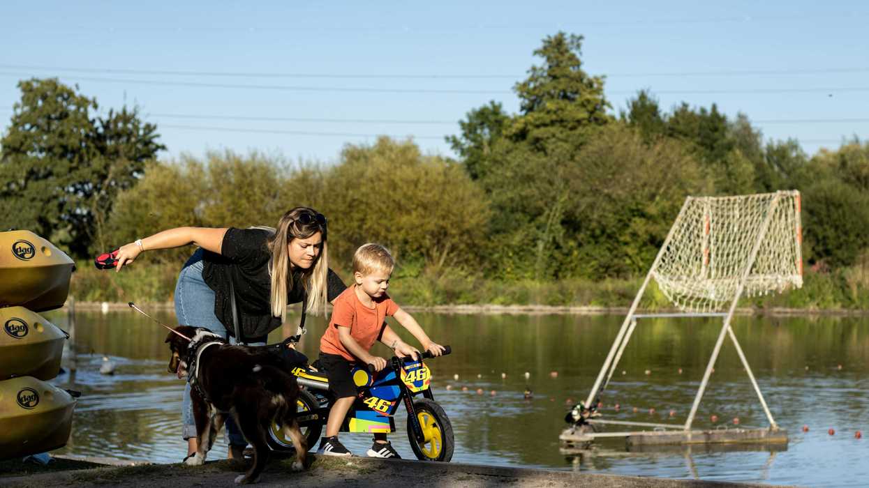 a woman and a child on a bike next to a lake.