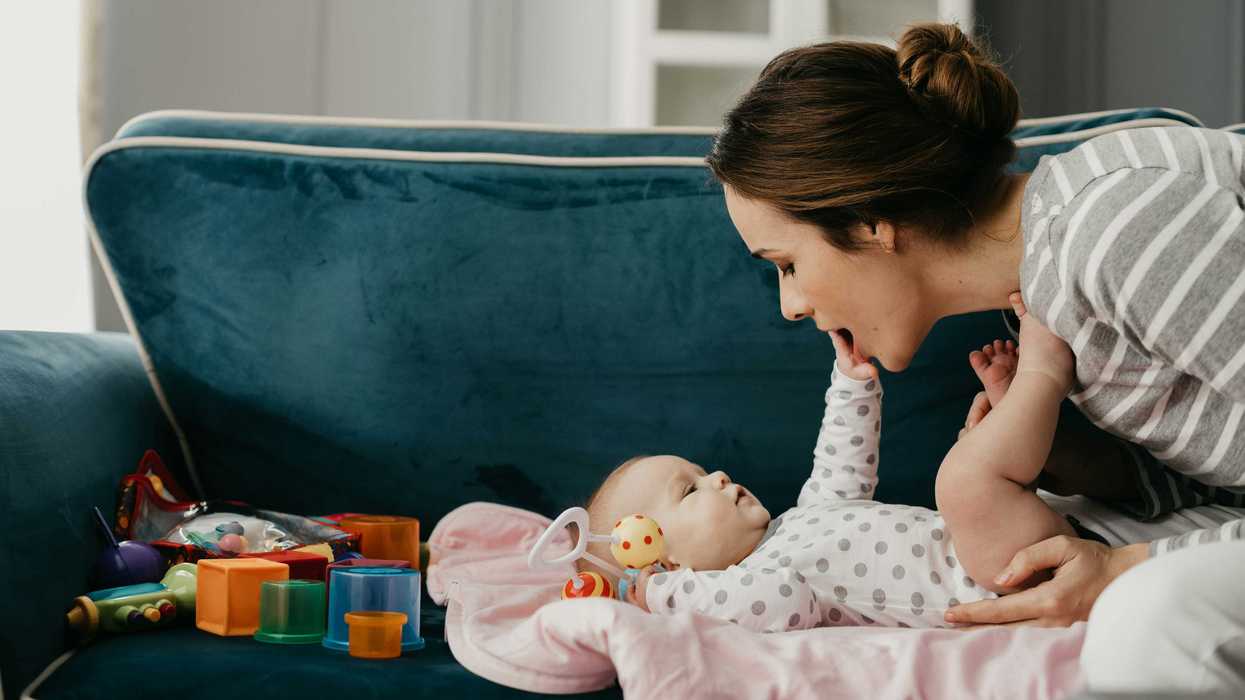 A woman and baby sit next to plastic toys