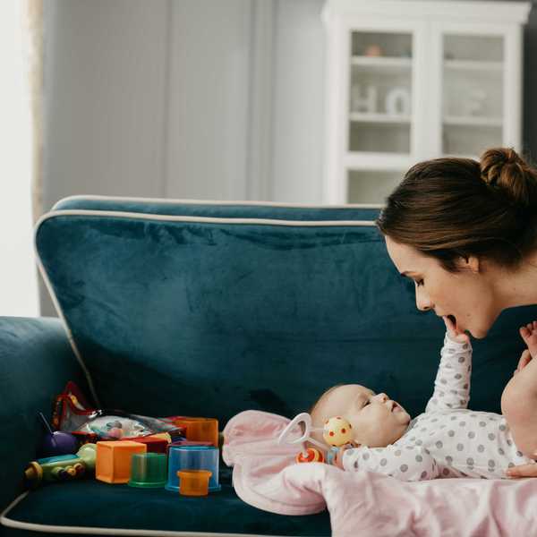 A woman and baby sit next to plastic toys