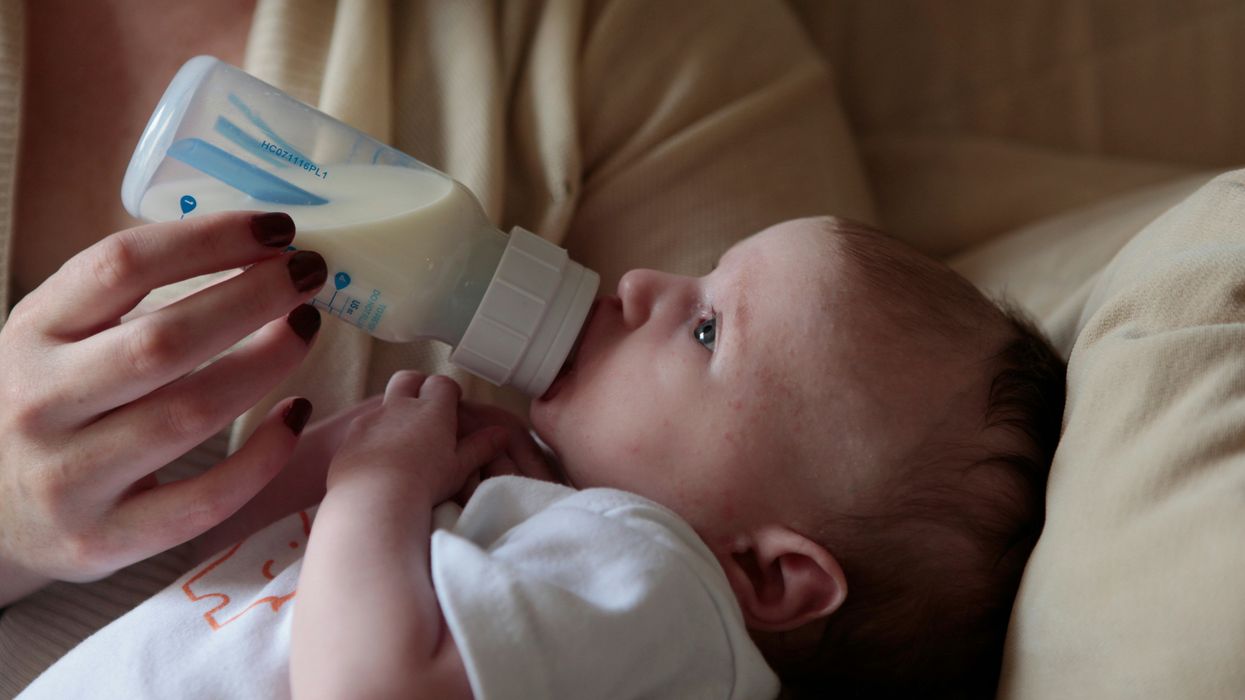 a woman feeding a baby with a bottle of milk