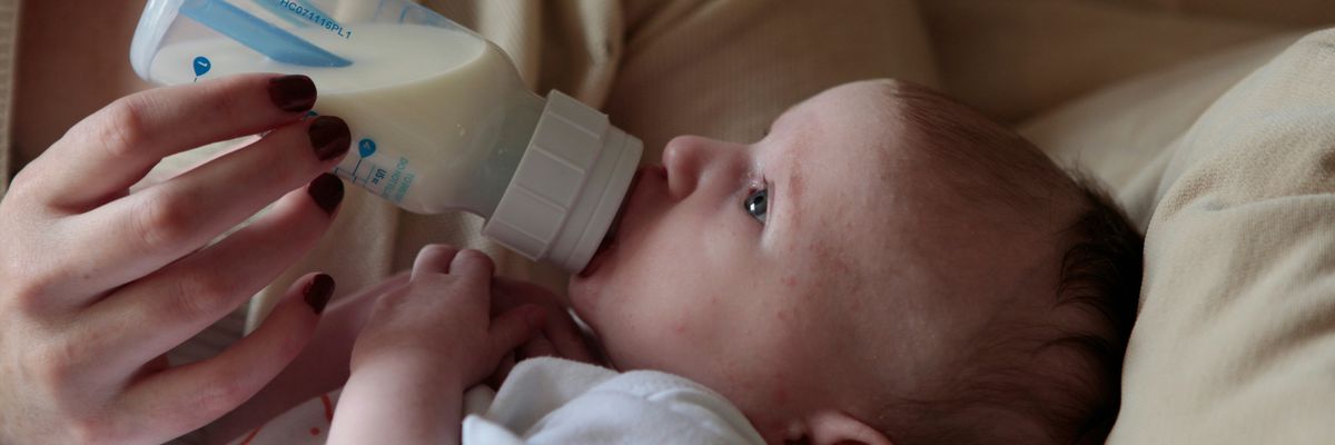 a woman feeding a baby with a bottle