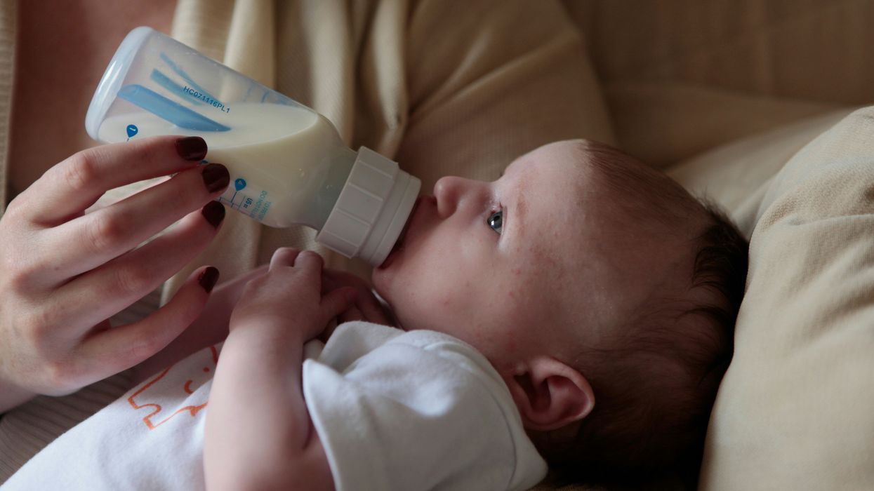 a woman feeding a baby with a bottle