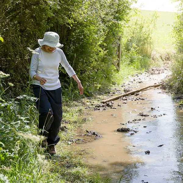 A woman hiking along a flooding stream