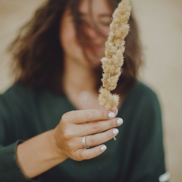 A woman holding a beige branch with small leaves on it
