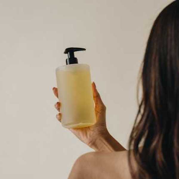 A woman holding a glass jar with liquid soap in it