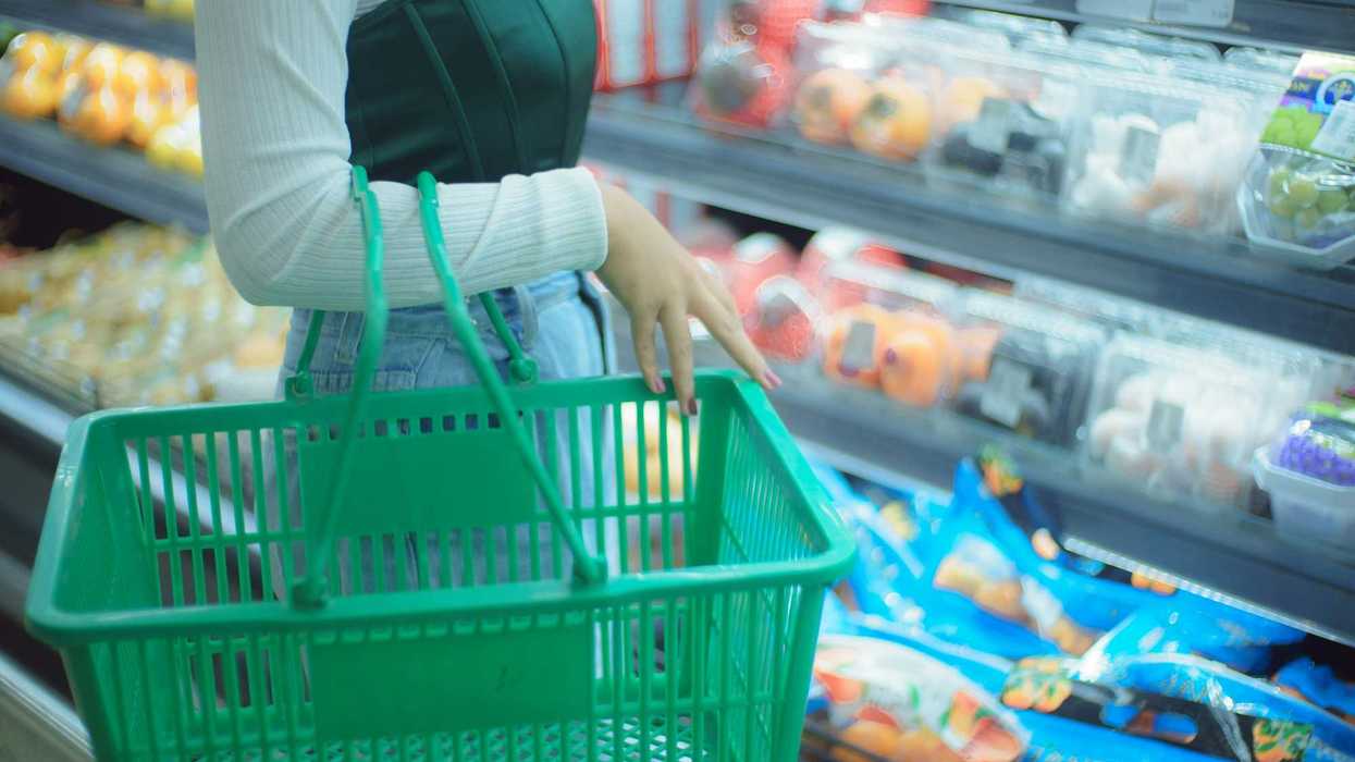 a woman holding a shopping basket in a grocery store.
