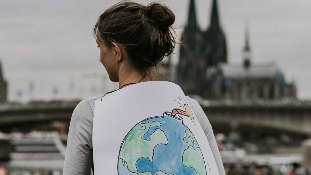 a woman holding a sign that says time is running out with a picture of Earth with a fuse attached.