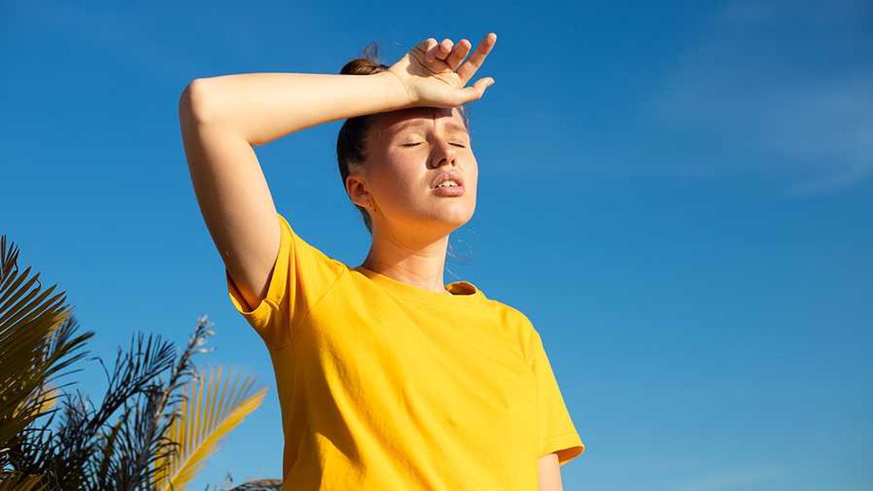 A woman holding her hand to her forehead on a hot day