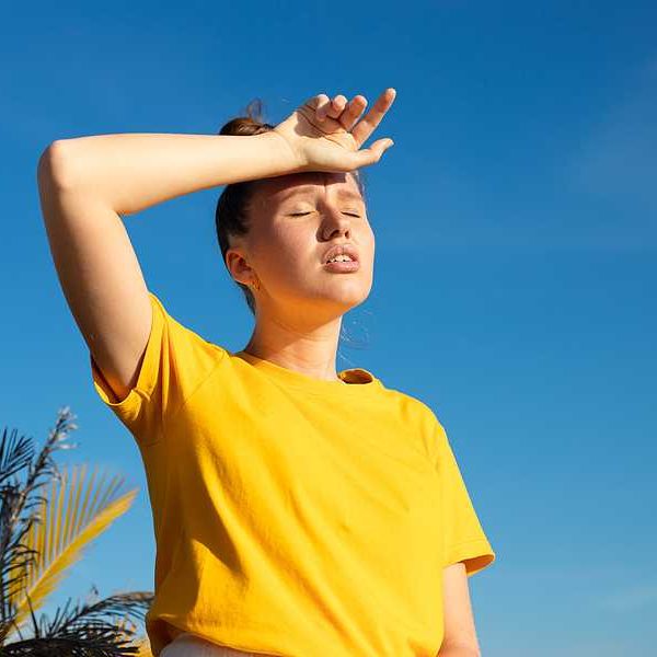 A woman holding her hand to her forehead on a hot day