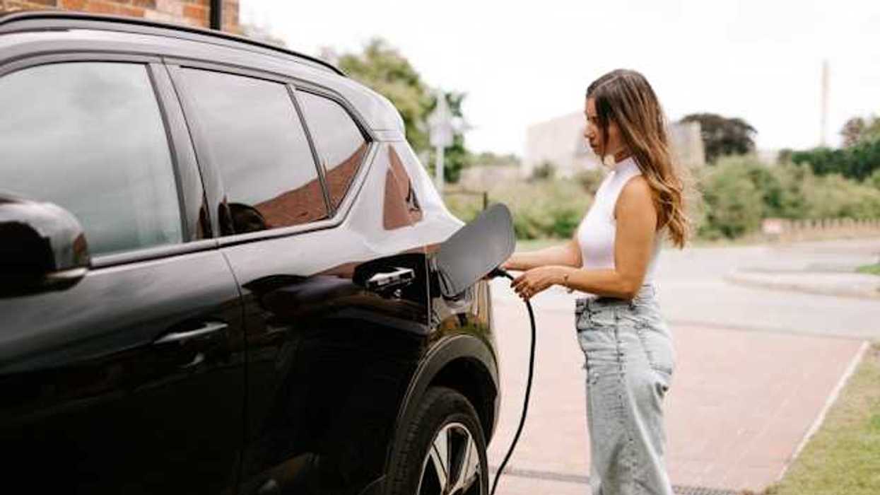 A woman hooking her electric vehicle up to a charger
