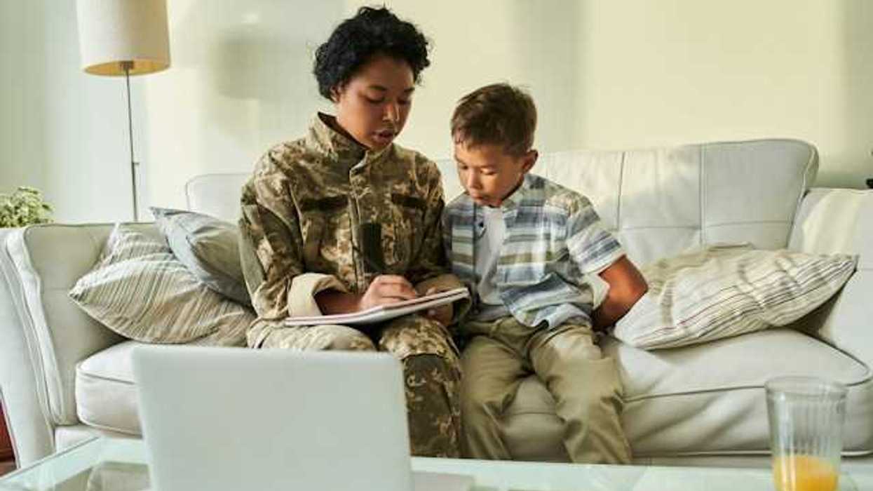A woman in military uniform helping her child with homework