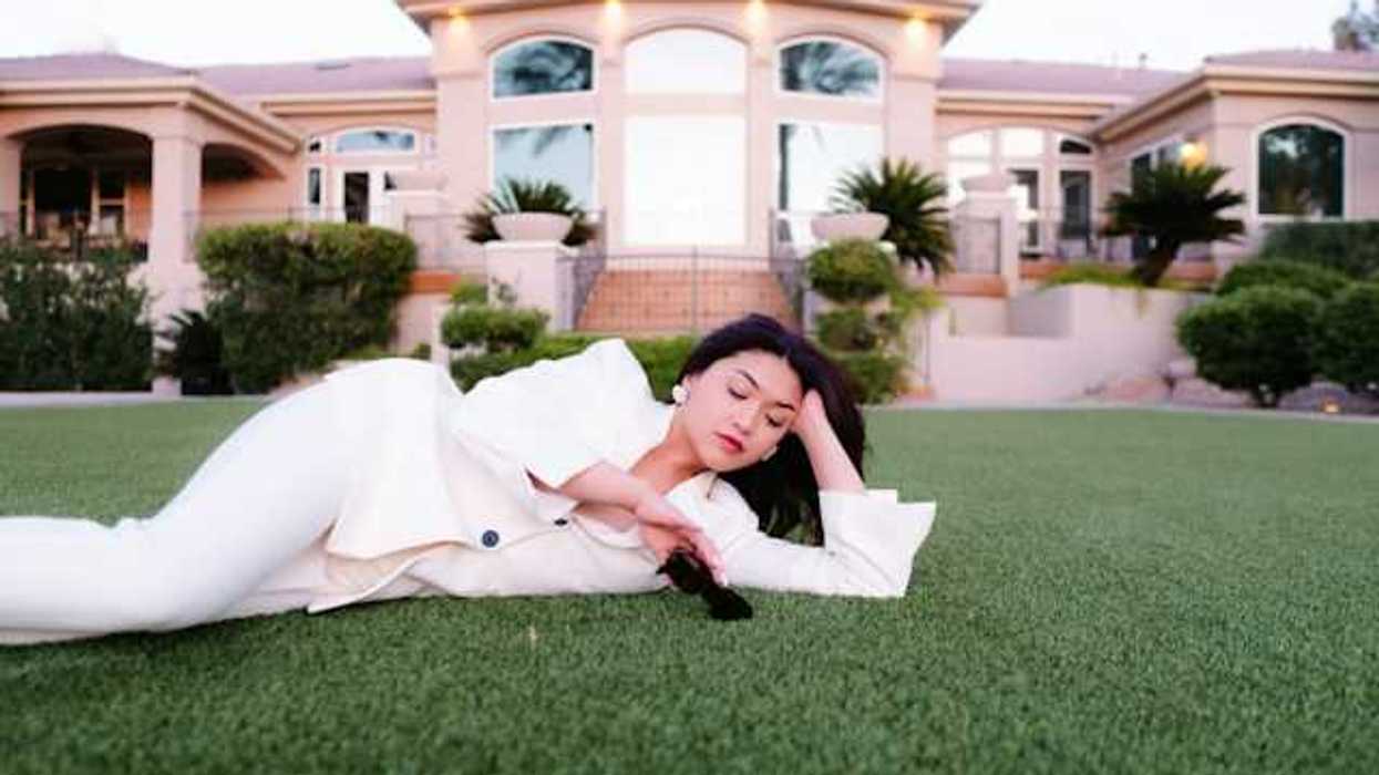 A woman laying on the grass in front of a large house