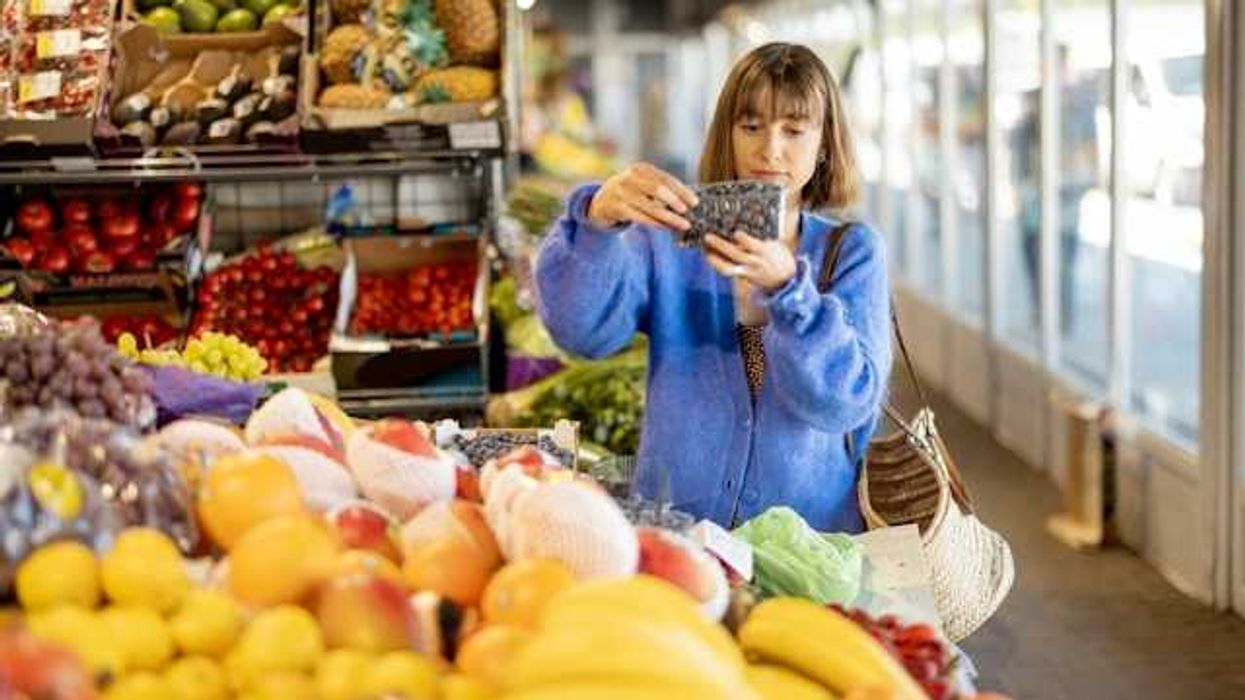 A woman looking at a container of berries in a grocery store