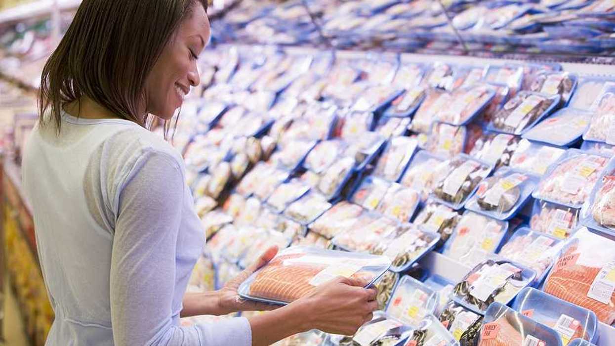 A woman looking at a fish filet in a grocery store