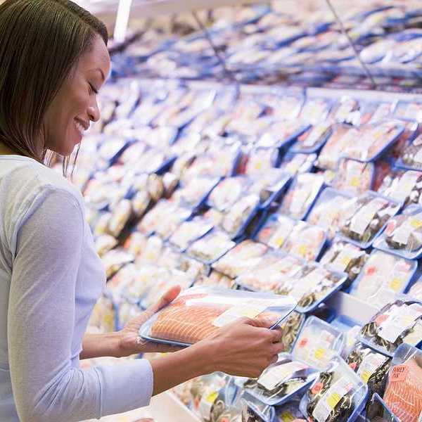 A woman looking at a fish filet in a grocery store