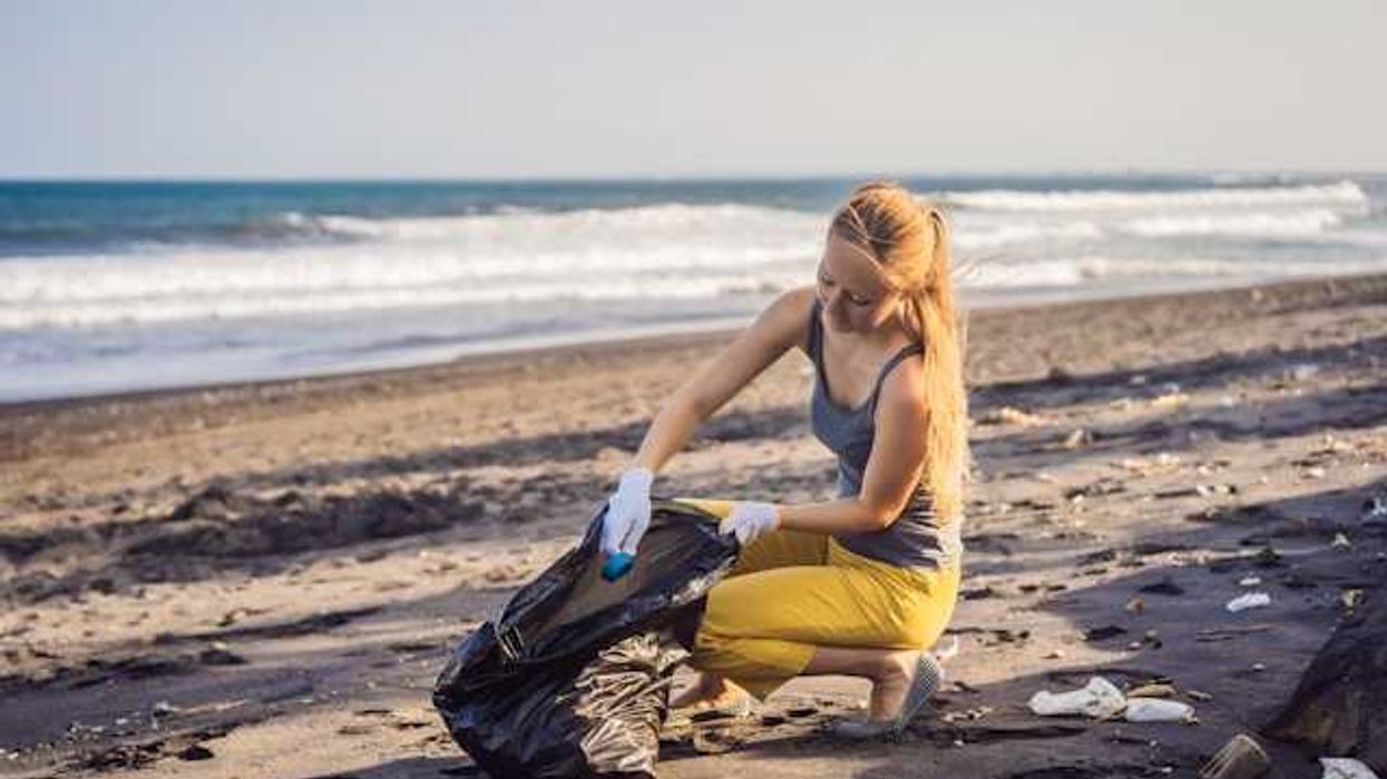 A woman on a beach cleaning up trash