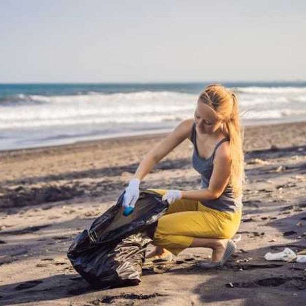 A woman on a beach cleaning up trash