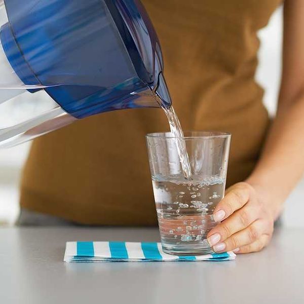 A woman pouring filtered water into a glass