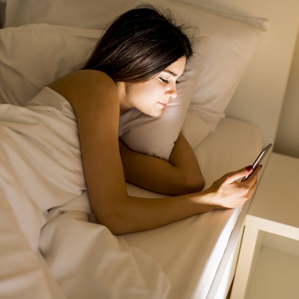 A woman reads her phone in bed