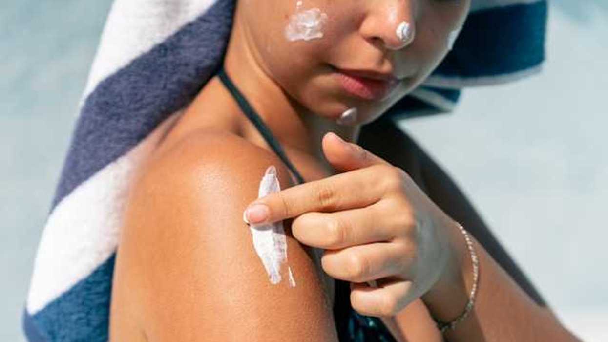 A woman rubbing white sunscreen on her shoulder
