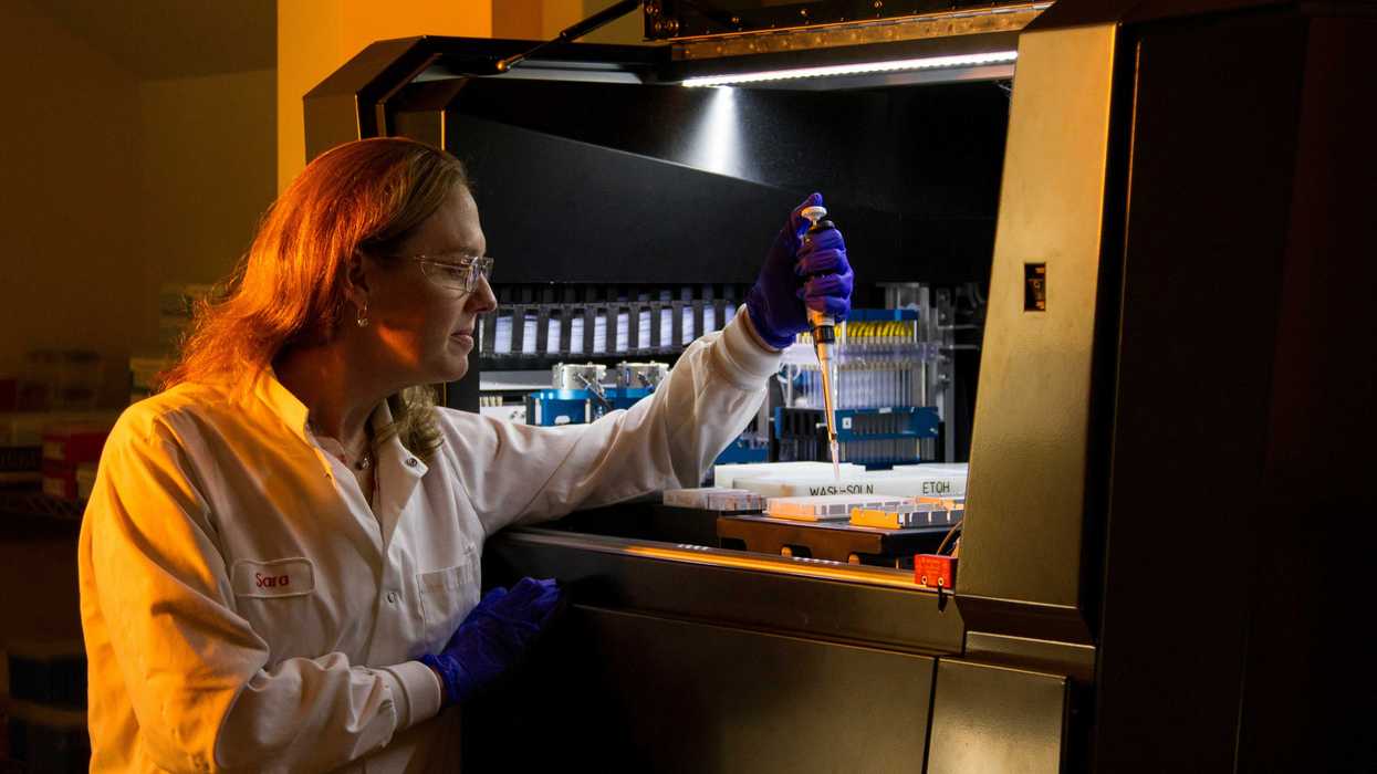 A woman scientist putting samples into a test tubes.