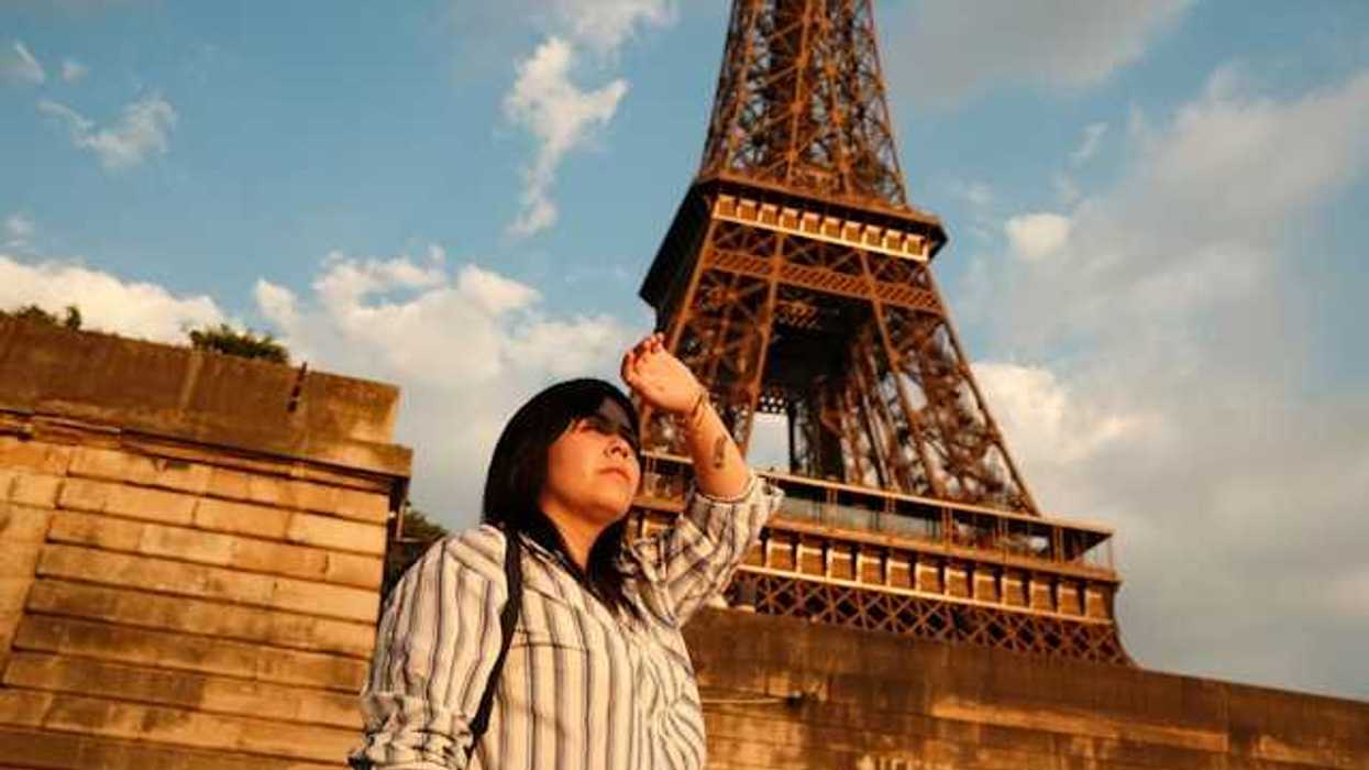 A woman shielding her eyes from the sun with the Eiffel Tower in the background