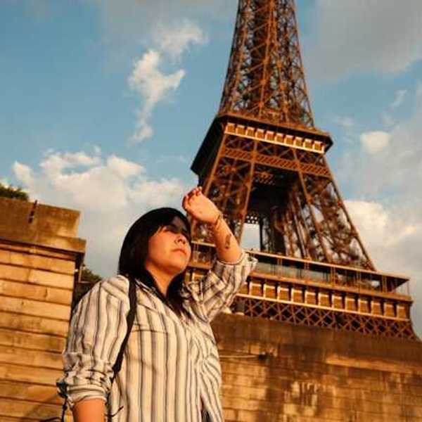 A woman shielding her eyes from the sun with the Eiffel Tower in the background