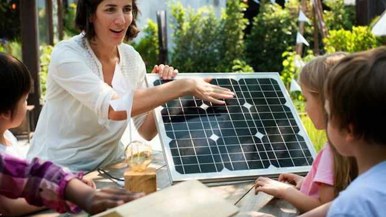 A woman showing a small solar panel to a group of children