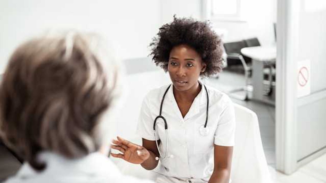 A woman sits facing a doctor