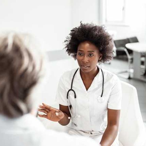 A woman sits facing a doctor