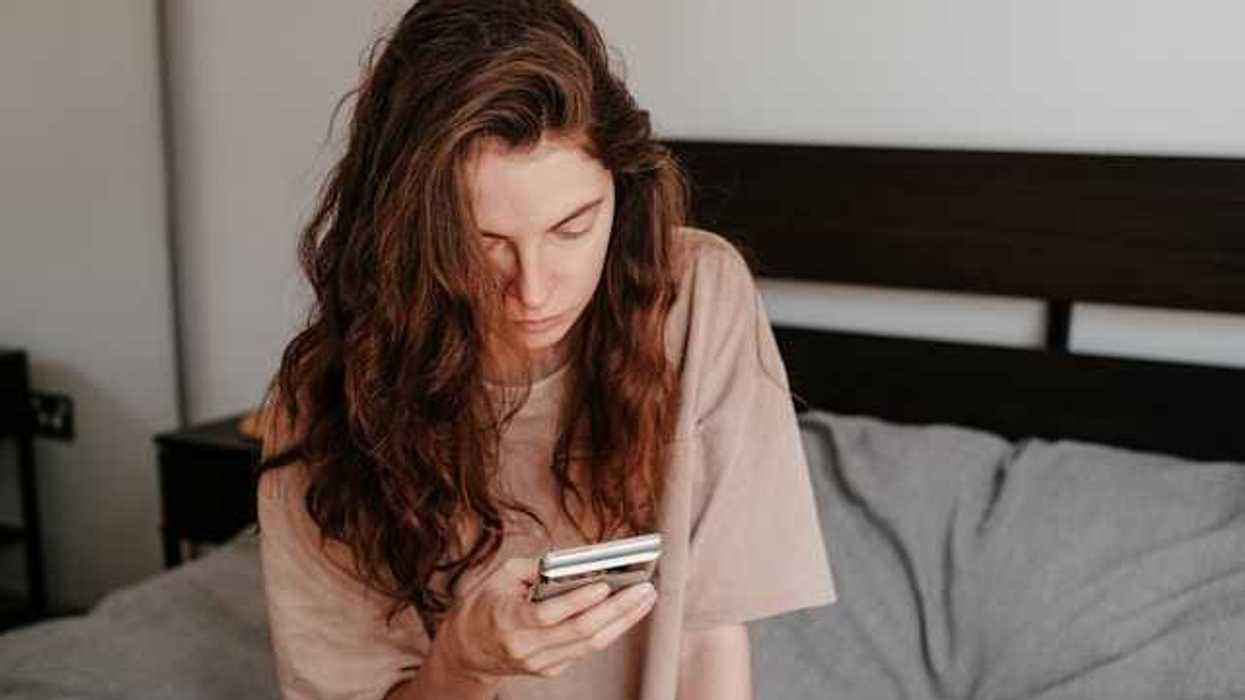 A woman sitting in bed looking at her phone