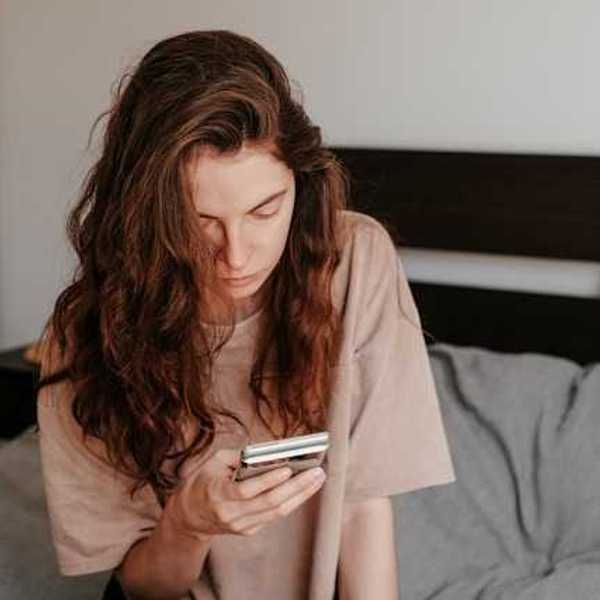 A woman sitting in bed looking at her phone