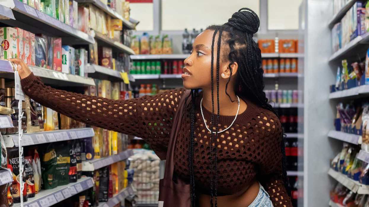 a woman standing in a store aisle looking at canned food.