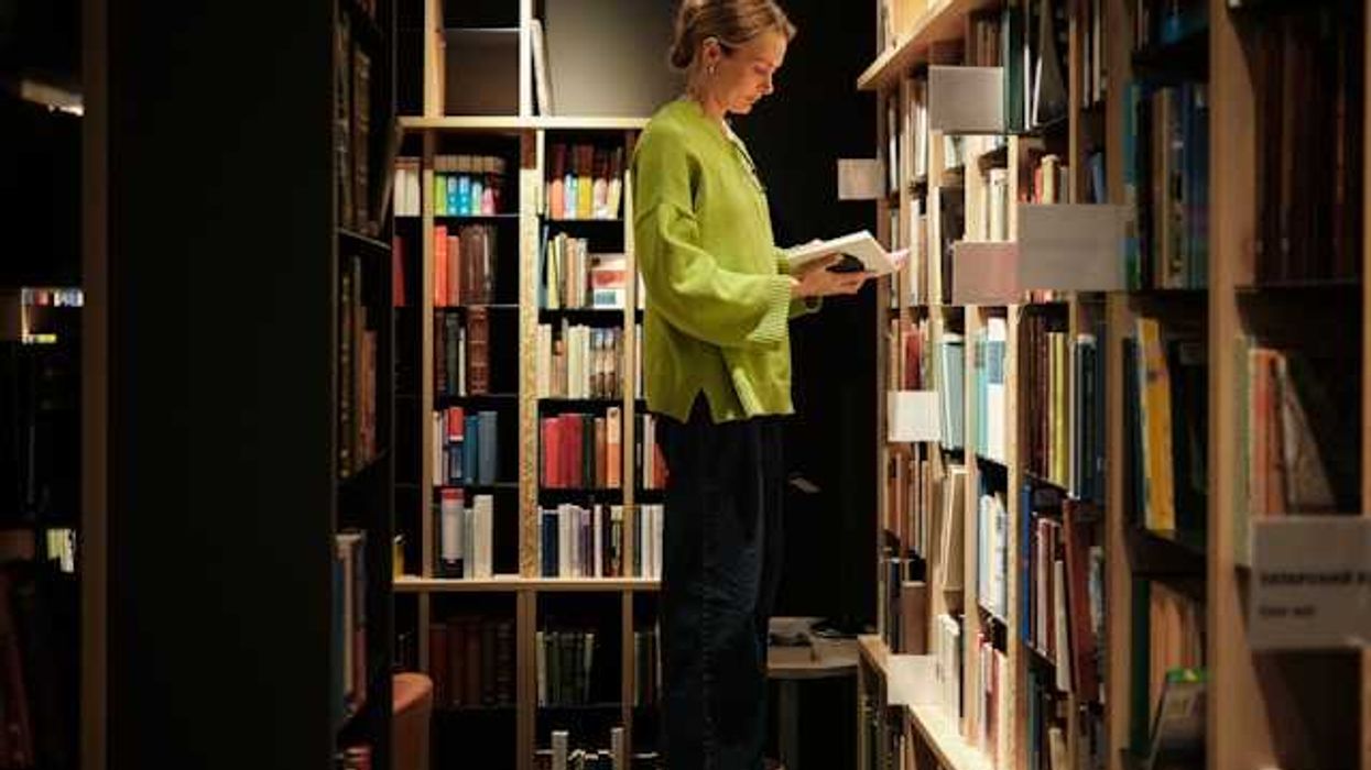 A woman standing on a stool in front of library bookshelves