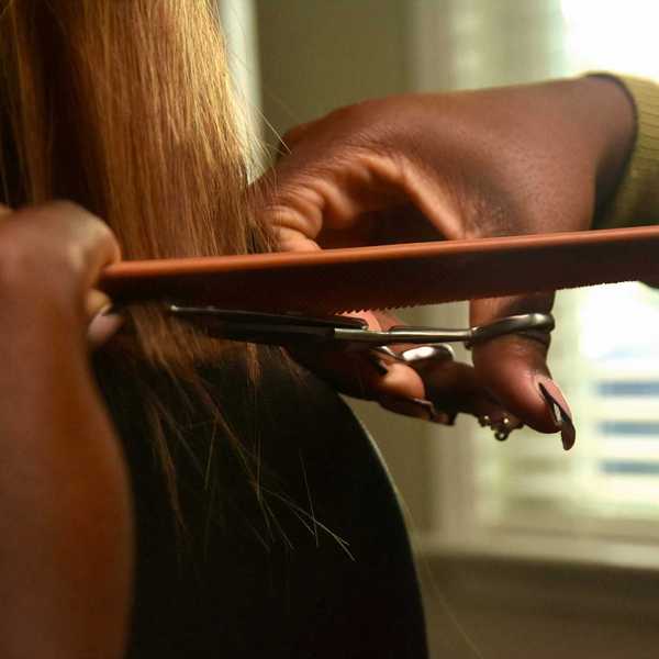 A woman styles another woman's hair