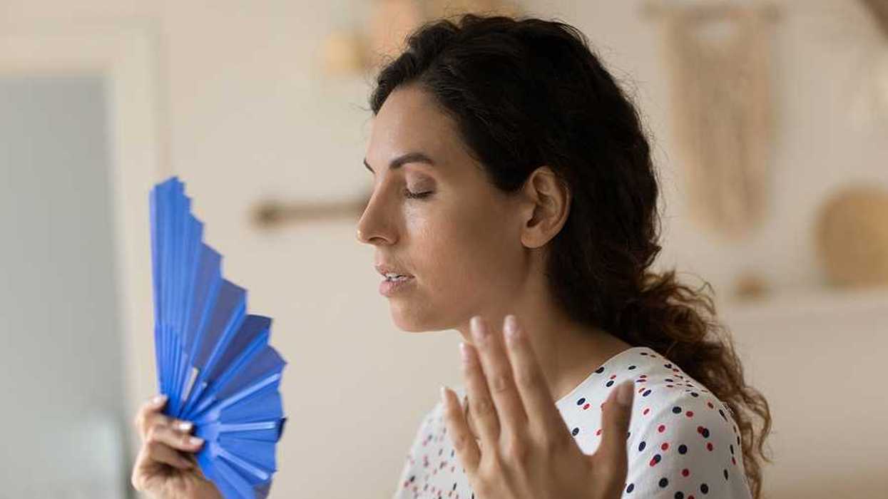 A woman using a blue fan to try to cool herself off
