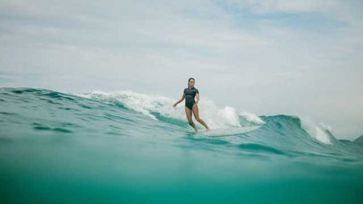 A woman wearing a wetsuit surfing a wave