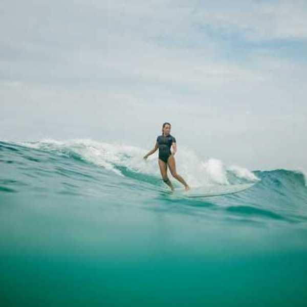A woman wearing a wetsuit surfing a wave